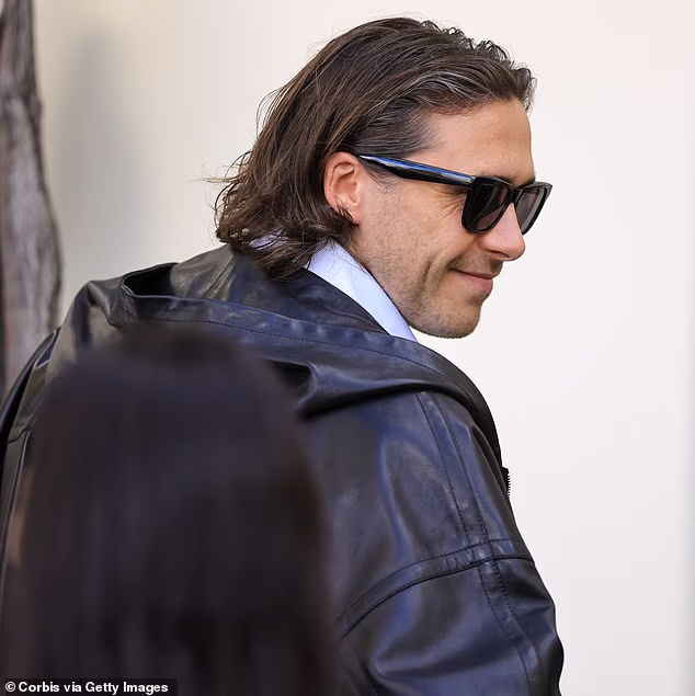 Brooklyn Beckham, 27, reveals salt and pepper flecks in his hair as he and Nicola Peltz arrive at the Balenciaga show – one day before estranged mum Victoria’s Paris Fashion Week event